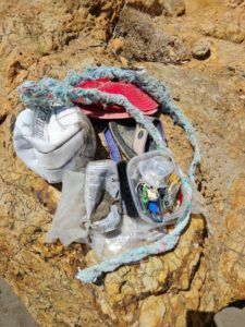 Trash collected at a beach featuring lots of fishing line, a volleyball, flip flop, bucket hat, and other plastic trash